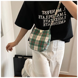 Detail view of the green plaid crossbody bag shown on model for size reference