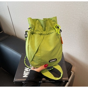 Close-up of vibrant neon green nylon bucket bag featuring a rubberized LUCKY logo patch