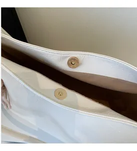 Close-up of pearl white glossy leather tote with golden magnetic buckles and texture
