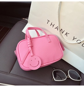 Pink lychee grain leather pillow bag with smiley charm on a car seat detail