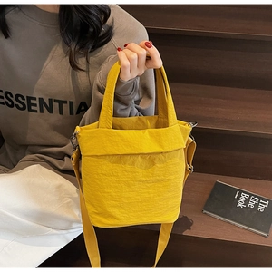 Close-up of yellow pleated nylon tote bag with adjustable shoulder strap and texture