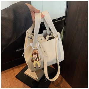 Detail view of off-white lychee texture tote bag with metallic studs and cartoon charm