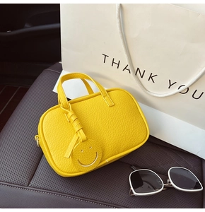 Yellow leather pillow bag with smiley charm and crossbody strap on car seat