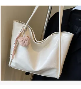 Detail of creamy white oil wax leather tote bag with soft pleated texture and pink bear charm