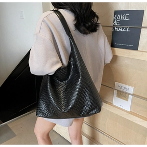 Close-up detail of the intricate woven leather texture on a large black tote bag