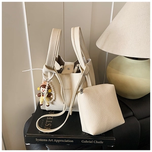 Close-up of beige lychee grain leather tote bag with small pouch and doll charm