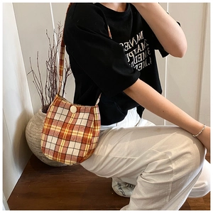 Detail of orange and yellow plaid tote bag with a cream button closure and soft fabric