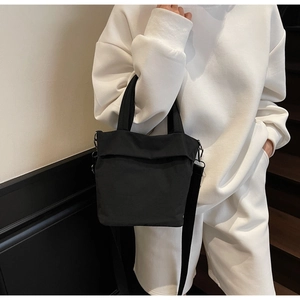 Close-up of black nylon tote bag with adjustable shoulder strap and minimalist design