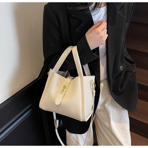 Sac à main chic crème avec motif litchi et fermoir doré tenu par un mannequin