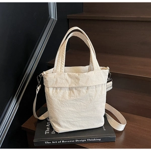 Detailed macro view of the cream-colored tote showing textured fabric and metal hooks