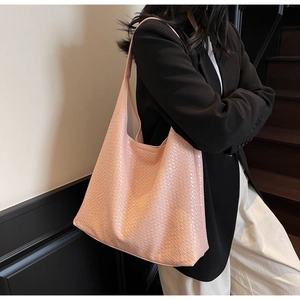 Close-up of pink woven texture tote bag worn by a model in a minimal professional setting