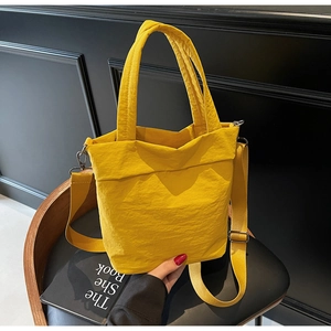 Detailed macro of bright yellow nylon tote bag featuring adjustable strap and silver metal buckle