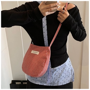 Detail of red and white gingham crossbody bag with fabric texture and brand label