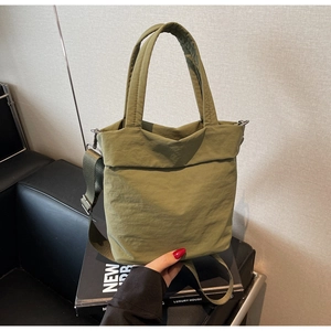 Detail of the olive green nylon crossbody bag with textured pleats and padded handle
