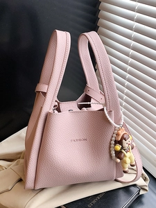 Pink litchi texture leather tote bag with FASHION text and cute doll charm