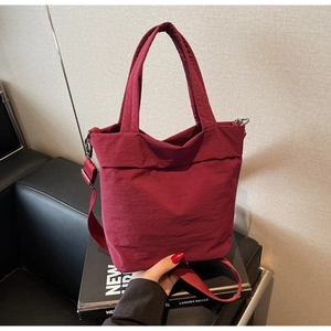 Detail of burgundy nylon tote bag with pleated design and detachable shoulder strap