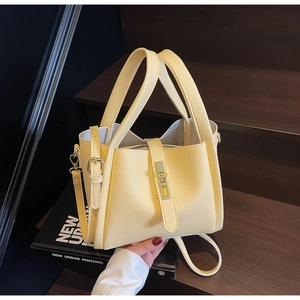 Détails de la texture du cuir litchi jaune clair et du fermoir en métal doré de ce sac chic