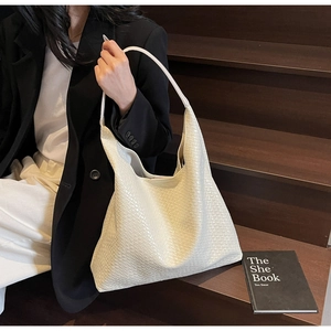 Close-up detail of cream woven hobo tote bag texture with minimalist shoulder strap