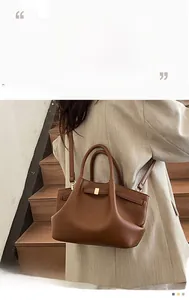 Close-up of brown litchi pattern leather tote bag with rectangular metal buckle detail