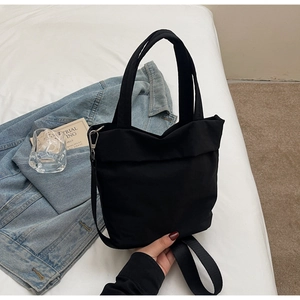 Detail of black canvas handbag showing durable fabric texture and adjustable strap