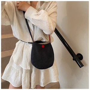 Detail of black crossbody bag featuring a red button and red checkered strap lining