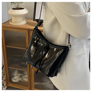 Gros plan du sac bandoulière en cuir ciré noir poli avec des boucles dorées chic