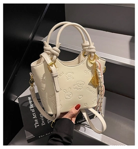 Detail of cream white bucket bag with embossed animal patterns and elegant silk scarf