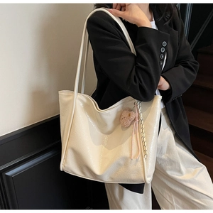Detailed side view of the cream oil wax leather tote bag with a pink bear charm
