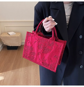 Close-up of red satin bridal handbag featuring intricate floral 3D relief embroidery