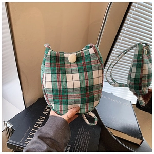 Detail of red and green plaid fabric bag with round white button on a mirror background