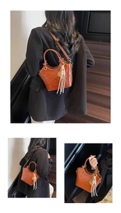 Close-up of brown leather bucket bag featuring embossed patterns and colorful tassel charm