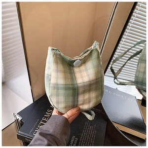 Close-up of green checkered woven fabric and blue button closure on a stylish tote bag