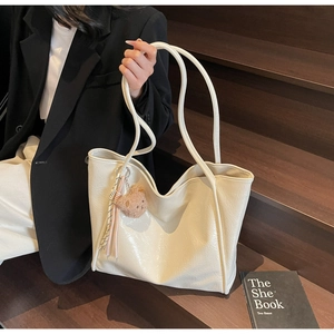 Detail of creamy off-white tote bag with oil wax leather texture and cute bear charm