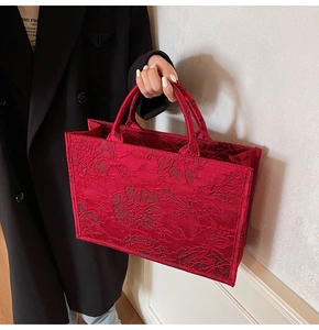 Close-up of elegant red bridal tote bag with floral jacquard embroidery and handles