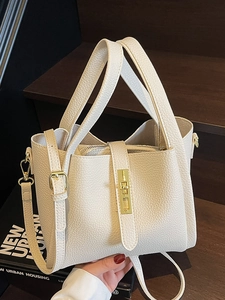 Sac à main élégant crème motif litchi avec fermoir doré sur marches en bois
