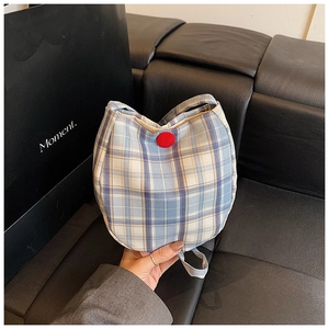 Close-up of blue and yellow plaid canvas bag featuring a distinctive red round button closure