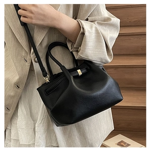 Detail of black lychee grain leather bucket bag with metallic lock and adjustable strap