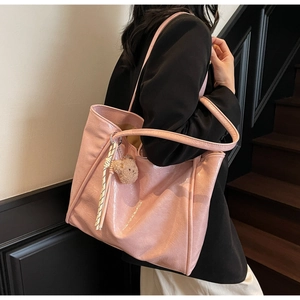 Close-up of bright pink oil wax leather tote bag with glossy texture and brown bear charm