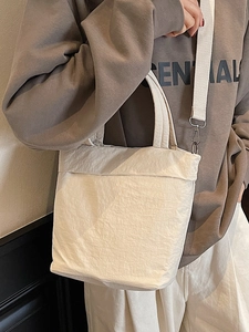 Minimalist white pleated crossbody bag with dual handles and adjustable shoulder strap