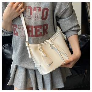 Sac seau blanc en forme de demi-lune porté à l'épaule dans un décor minimaliste