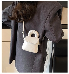 Detail of white mini crossbody bag with fluffy handle and cute kitty embroidery on the back