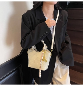 Detail of cream white bucket bag with embossed cartoon patterns and knotted top handle