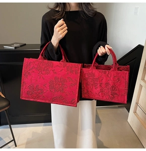 Detail of red jacquard handbags in two sizes featuring elegant floral embossed patterns
