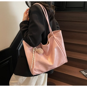Pink oversized oil wax leather tote bag shown with a cute plush bear charm on a model