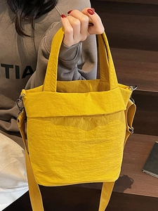 Minimalist yellow pleated nylon tote bag with top handles and adjustable crossbody strap