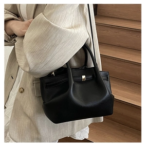 Detail of black lychee grain leather bucket bag with gold lock and pleated texture