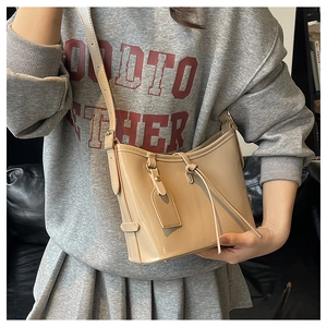 Détail de la bandoulière réglable et texture cuir ciré brillant du sac seau beige