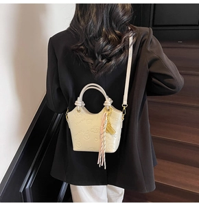 Detail view of the cream white bucket bag with embossed cartoon bear and rabbit pattern
