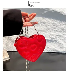 Detailed view of red heart-shaped bag with embossed pattern and silver chain strap