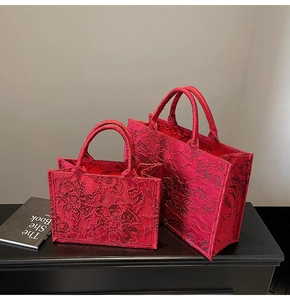 Detailed close-up of red tote bags with luxury 3D floral embroidery and lace texture